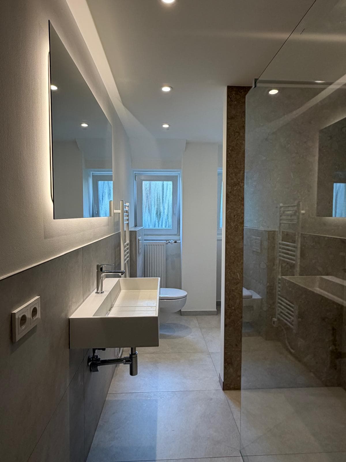 Modernisiertes Badezimmer mit bodengleicher Walk-in-Dusche und großformatigen Fliesen