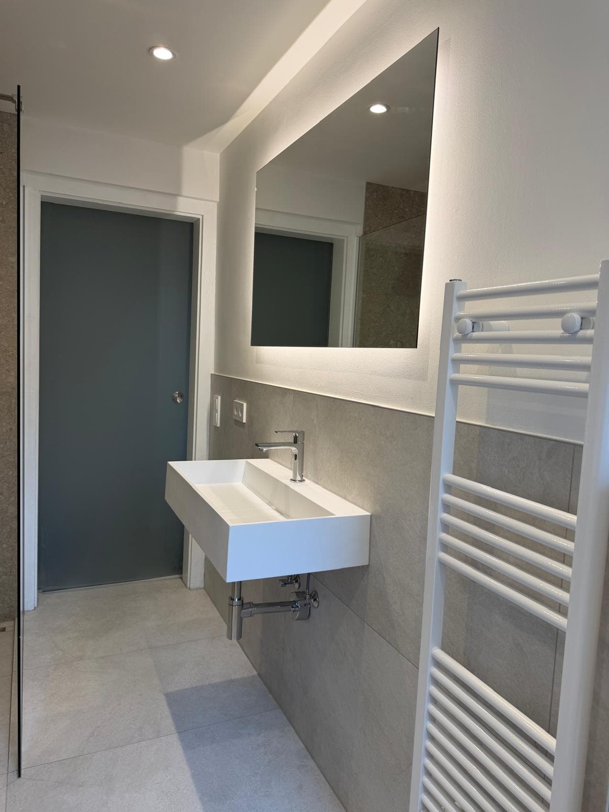 Modernisiertes Badezimmer mit bodengleicher Walk-in-Dusche und großformatigen Fliesen, weitere Projektansicht 2