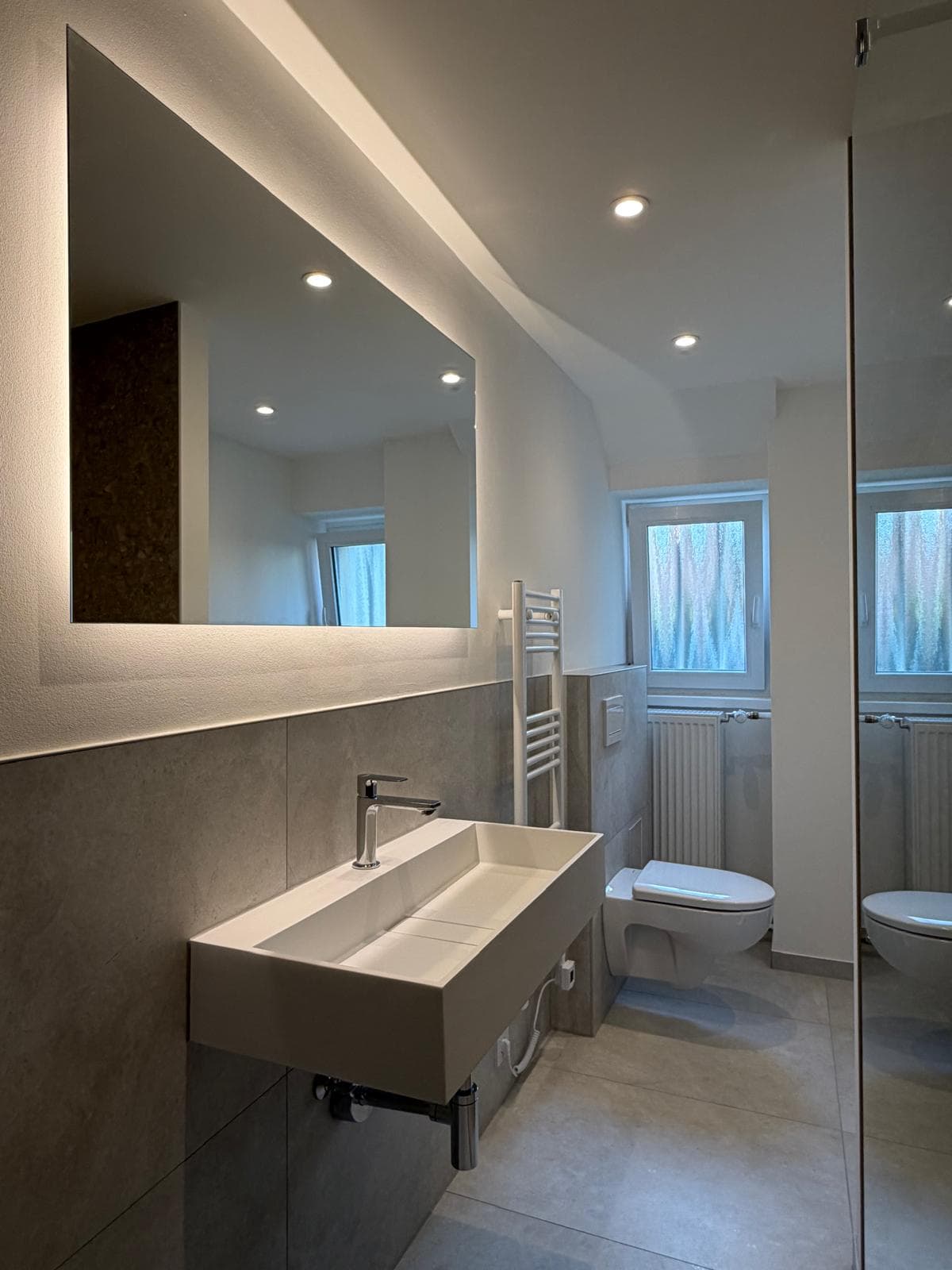 Modernisiertes Badezimmer mit bodengleicher Walk-in-Dusche und großformatigen Fliesen, weitere Projektansicht 1